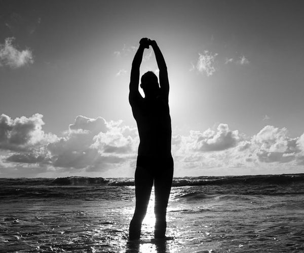 Silhouette of a person stretching during sunrise, full of energy.